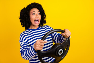 Portrait of screaming girl with afro hairstyle holding steering wheel staring at accident empty...