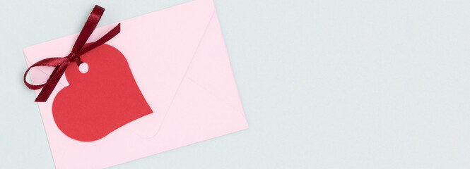 Banner with red empty tag in a heart shape with tied ribbon bow and envelope on a blue background. Place for text.