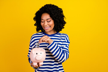 Portrait of smart nice cheerful girl with chevelure wear striped pullover put dollar in money box...