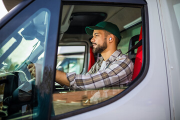 Young truck driver having eraphones while he drives the truck.