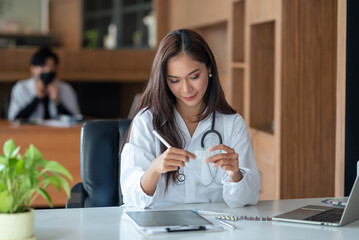 Asian female doctor checking medicine in doctor's office. Health and medical diagnosis concept.