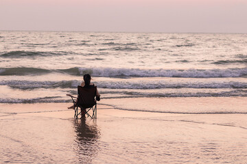 Fototapeta na wymiar Asian woman sitting with relax in chair at the sea watching the blue horizon. peaceful and tranquil mood at sunset.