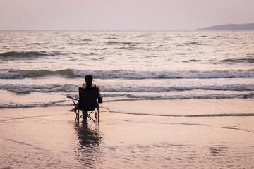 Asian woman sitting with relax in chair at the sea watching the blue horizon. peaceful and tranquil mood at sunset.