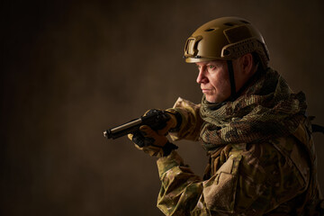 Portrait of a man equipped as a military man with an airsoft gun and helmet