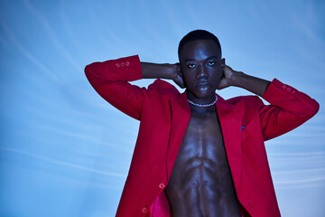 handsome sexy african american man in red vivid blazer looking at camera on blue watery background