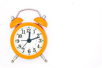 Over head view of a vintage tiny orange alarm clock isolated on white background positioned on the left side and copy space on the right. 12:12 AM.