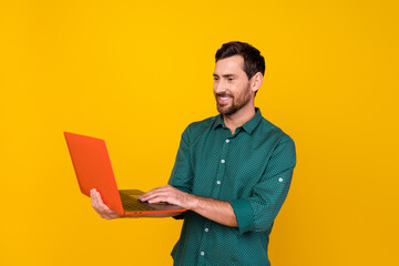 Photo of intelligent smart guy with beard dressed dotted shirt look at laptop typing email isolated...
