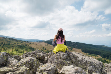Naklejka na ściany i meble Woman sitting on a rocks looking the city of Sofia in the summer mountain 