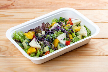 French salad with Camembert cheese. Healthy food. Takeaway food.  On a wooden background.