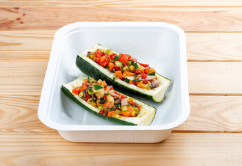Zucchini stuffed with vegetables. Vegetarian food. Takeaway food. On a wooden background.