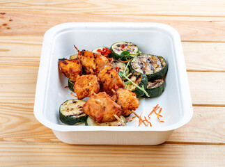 Grilled chicken kebab with zucchini. Healthy diet. Takeaway food.  On a wooden background.