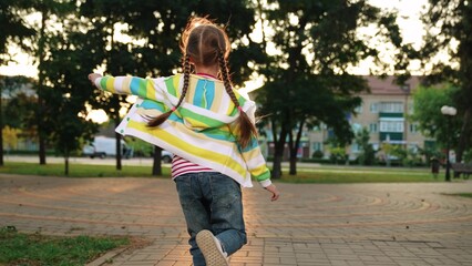 little girl running through park sunset, happy family, running foot along road kid girl daughter,...