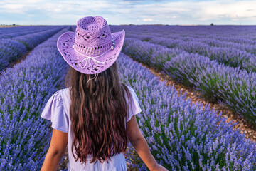 Young girl in the lavender field and cloudy sky at the background. Brihuega, Spain.