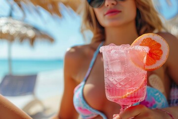 A woman enjoys a refreshing cocktail in her swimwear while basking in the warm summer sun at the beach
