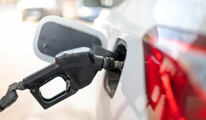 The nozzle fuel fill oil into car tank at pump gas station