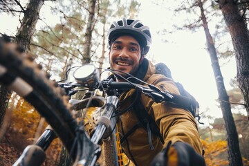 Fototapeta premium A determined man, his face obscured by a helmet, rides his bicycle through a lush outdoor setting, surrounded by towering trees, embodying freedom and adventure in his clothing and the way he confide