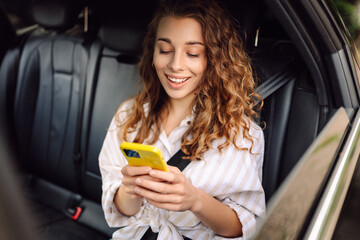 Young woman smile and use mobile phone touching the screen inside the car while travel. The concept...
