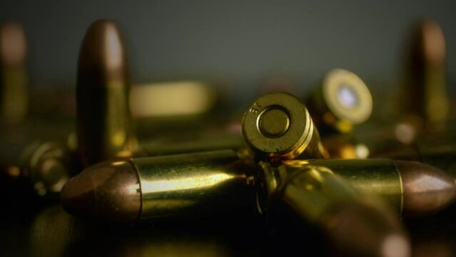 Gun Bullets Ammunition Close Up Ammo Zoom Out. Zoom out from a few bullets huddled together on a table. Tracking shot