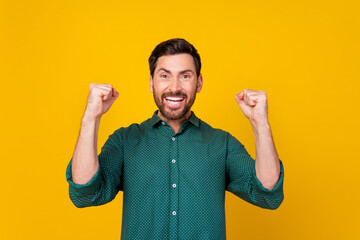 Photo of ecstatic satisfied guy dressed dotted shirt raising fists up screaming yeah win betting...