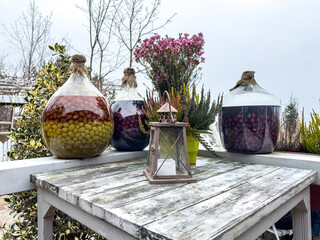 Demijohns containing seasoned fruit liqueurs from gooseberry, cherries and plums on an old wooden table