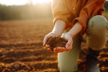 Farmer holding soil in hands close-up. Organic gardening, agriculture. Cultivated dirt, earth, ground, brown land background, nature. 