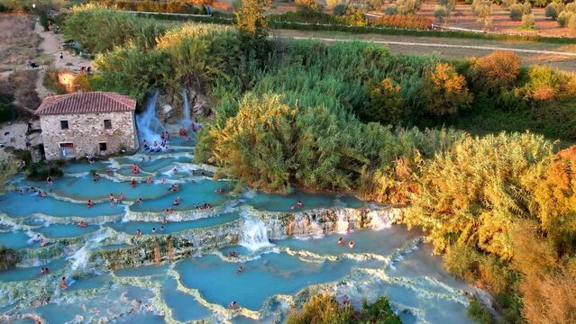Most famous natural thermal hot spings pools in Tuscany - scenic Terme di Mulino vecchio ( Thermals of Old Windmill) in Grosseto province. high angle drone shoot
