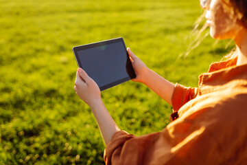 A woman farmer with a modern tablet in green field. Innovative smart farm system technology, agricultural management.