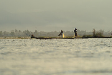 Burmese fisherman casting or throwing a net for catching freshwater fish in Unle lake, natural...
