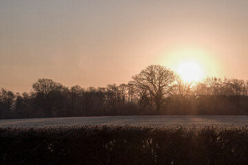 sunrise over the countryside on a cold frosty winter day with orange sky in the background