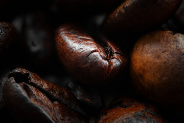 Close up macro photograph of whole roasted coffee beans rich and dark. Texture and grain. Wooden table worktop. Background