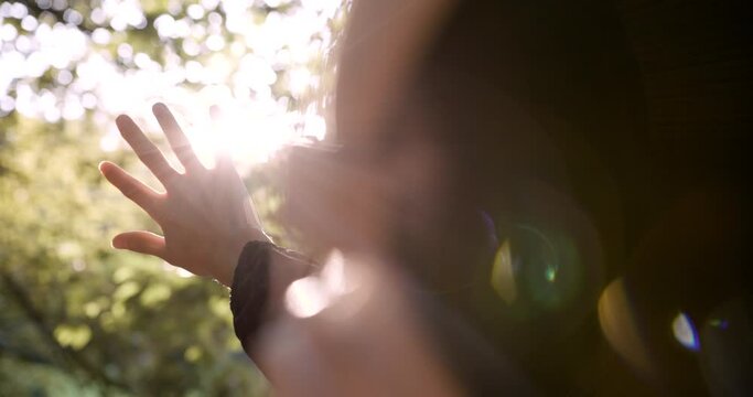 Girl looks at the sun through her hand