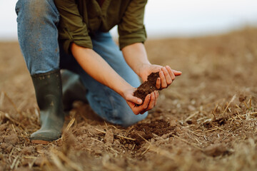 Farmer holding soil in hands close-up. Organic gardening, agriculture. Cultivated dirt, earth, ground, brown land background, nature. 