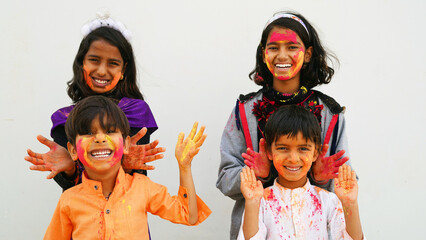 Happy Cute Smiling looking kids playing with paints in their fingers. Holi Festival of colors