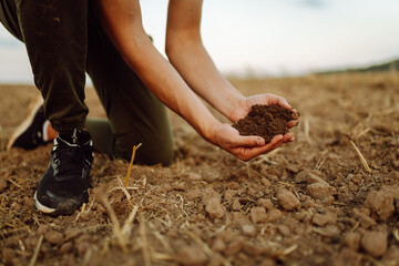 Farmer holding soil in hands close-up. Organic gardening, agriculture. Cultivated dirt, earth,...