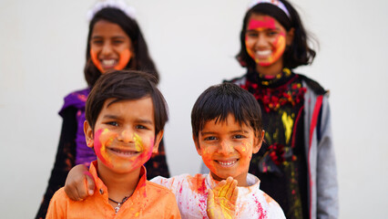 Happy Cute Smiling looking kids playing with paints in their fingers. Holi Festival of colors