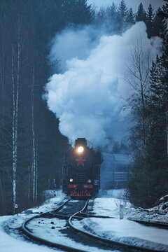 View of a steam locomotive train crossing the forest in winter, Ruskeala Express, Republic of Karelia, Russia.