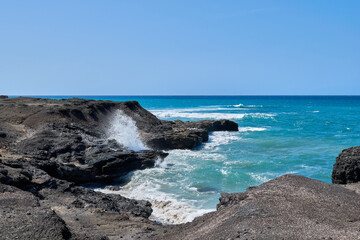 The Atlantic Ocean in Jandia with clear sky and mountains in the back and waves breaking on the...