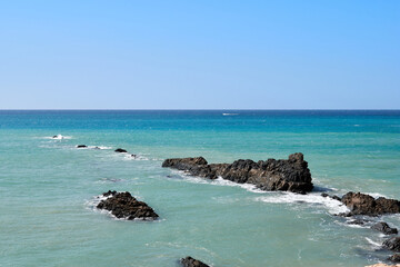 The Atlantic Ocean in Jandia with clear sky and mountains in the back and waves breaking on the shore
