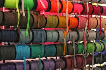 Bobbins with various colorful ribbons on counter in store. Needlework and sewing supplies. Colorful ribbon on rack in craft shop. Artisan and handicraft material. DIY hobby concept
