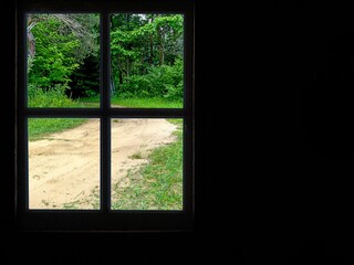 Offset windowpane on a black wall with dirt road in a woodland scene 