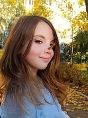 Obraz premium Cute little girl in autumn park holding bunch of yellow leaves