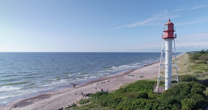 Aerial drone orbit shot of old iron lighthouse on sandy Baltic sea coast in Pape, Latvia