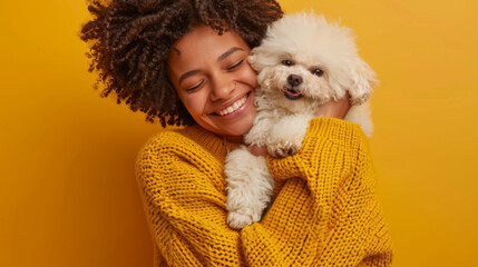 A joyful woman in a yellow knit sweater lovingly embraces her fluffy white dog, sharing a moment of affection.