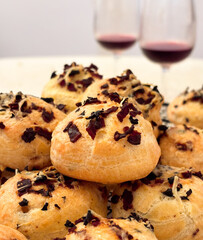 French savory choux dough cheese puff filled with crispy fried bacon. It's made of choux pastry mixed with cheese. Glass of red wine in background. It's a Burgundy specialties appetizer.