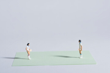 Photography of miniature people and toy figures, tennis players in action on a green sheet of paper...