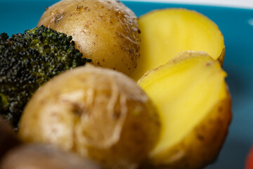 Close up of freshly roasted young potatoes on a plate next to fried broccoli crown