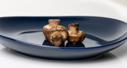 Couple of cooked mushrooms on porcelain plate