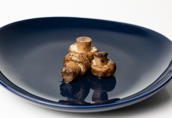 A navy blue plate adorned with three fried portobello mushrooms.
