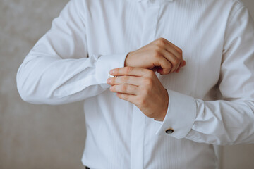 The man put on his shirt and straightens cufflinks. The groom fasten cufflinks on the cuffs of the...