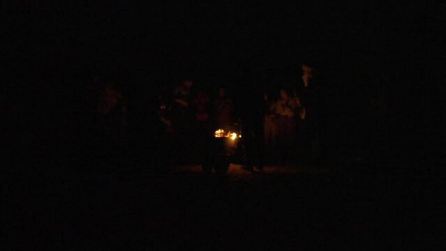 Berber musicians dancing and playing drums at night in the Mergouza Sahara desert around campfire long shot